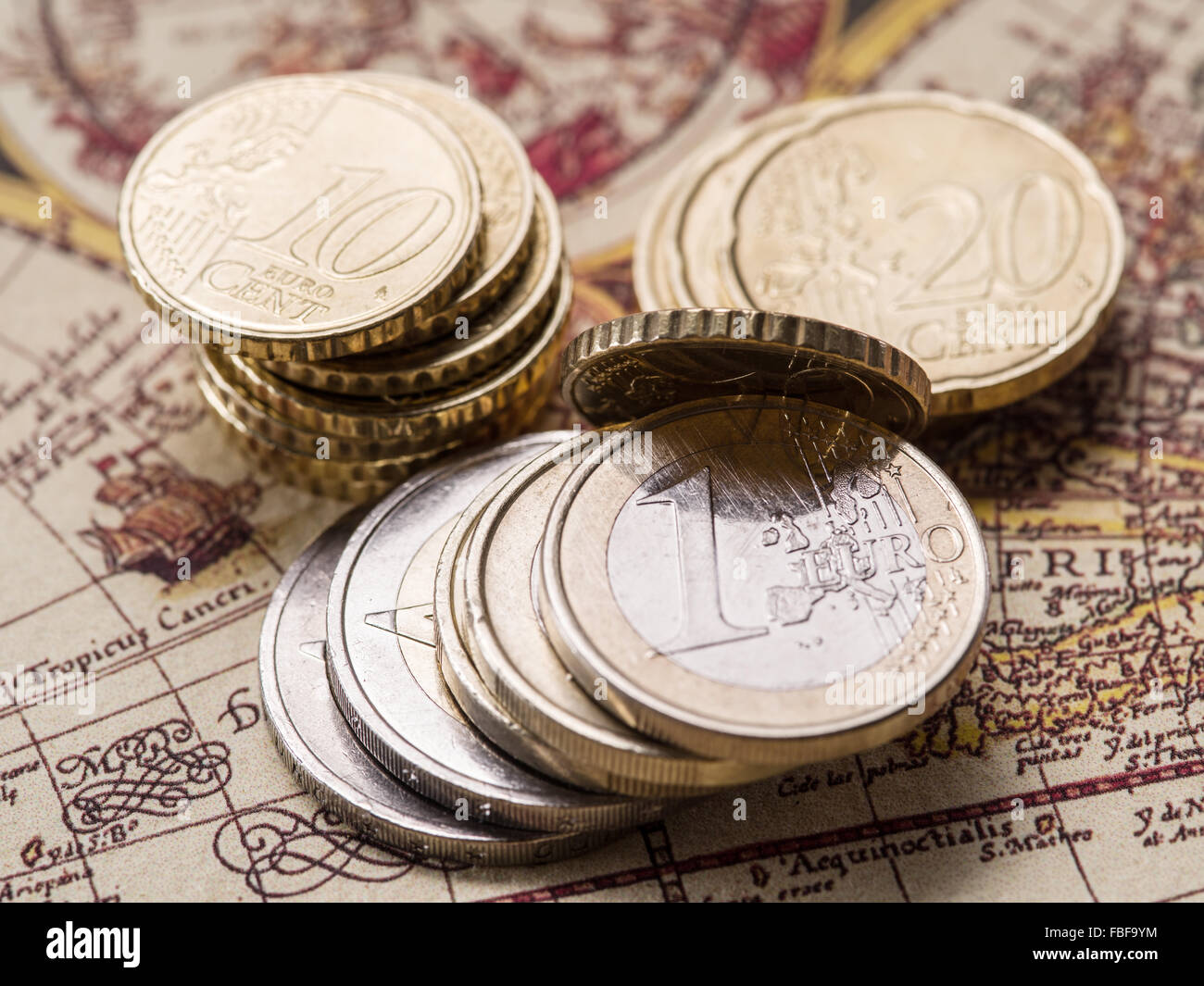 Euro coins over the old world map. Macro picture. Stock Photo