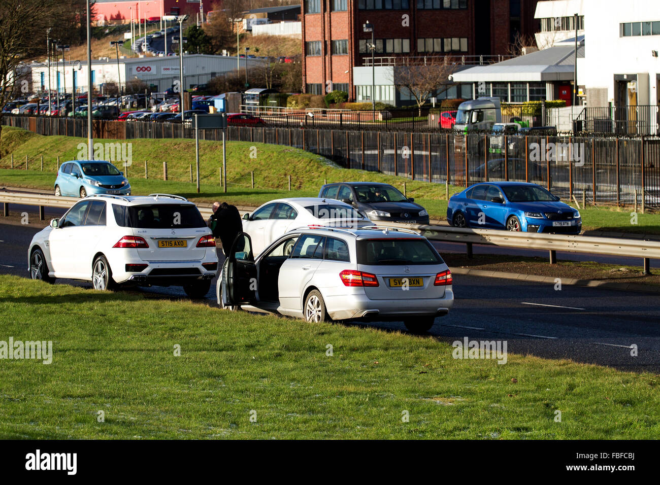 Motorist topping up a Mercedes-Benz car with petrol on the busy dual carriageway roadside in Dundee, UK Stock Photo