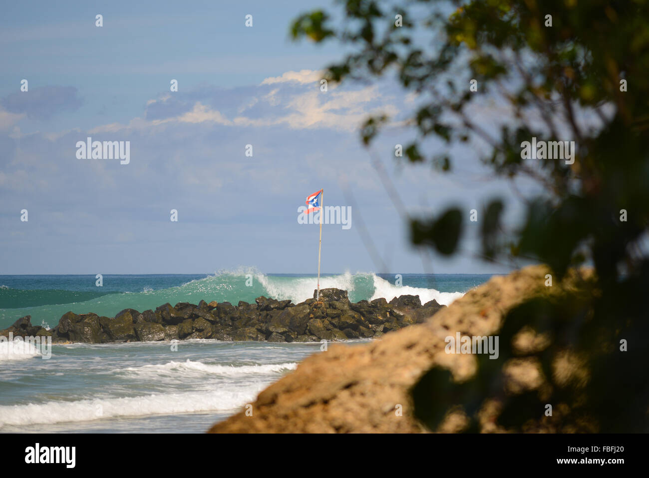 Puertorican flag and waves crashing at Dome's Beach. Rincon, Puerto Rico. USA territory. Caribbean Island. Stock Photo
