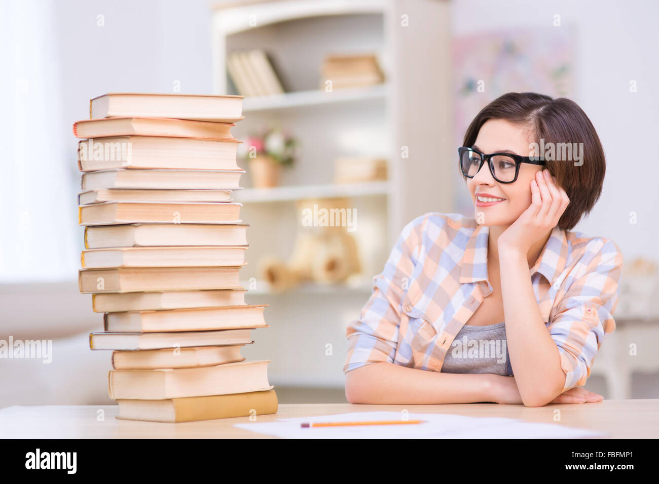 Young girl sitting in front near pile of books Stock Photo - Alamy