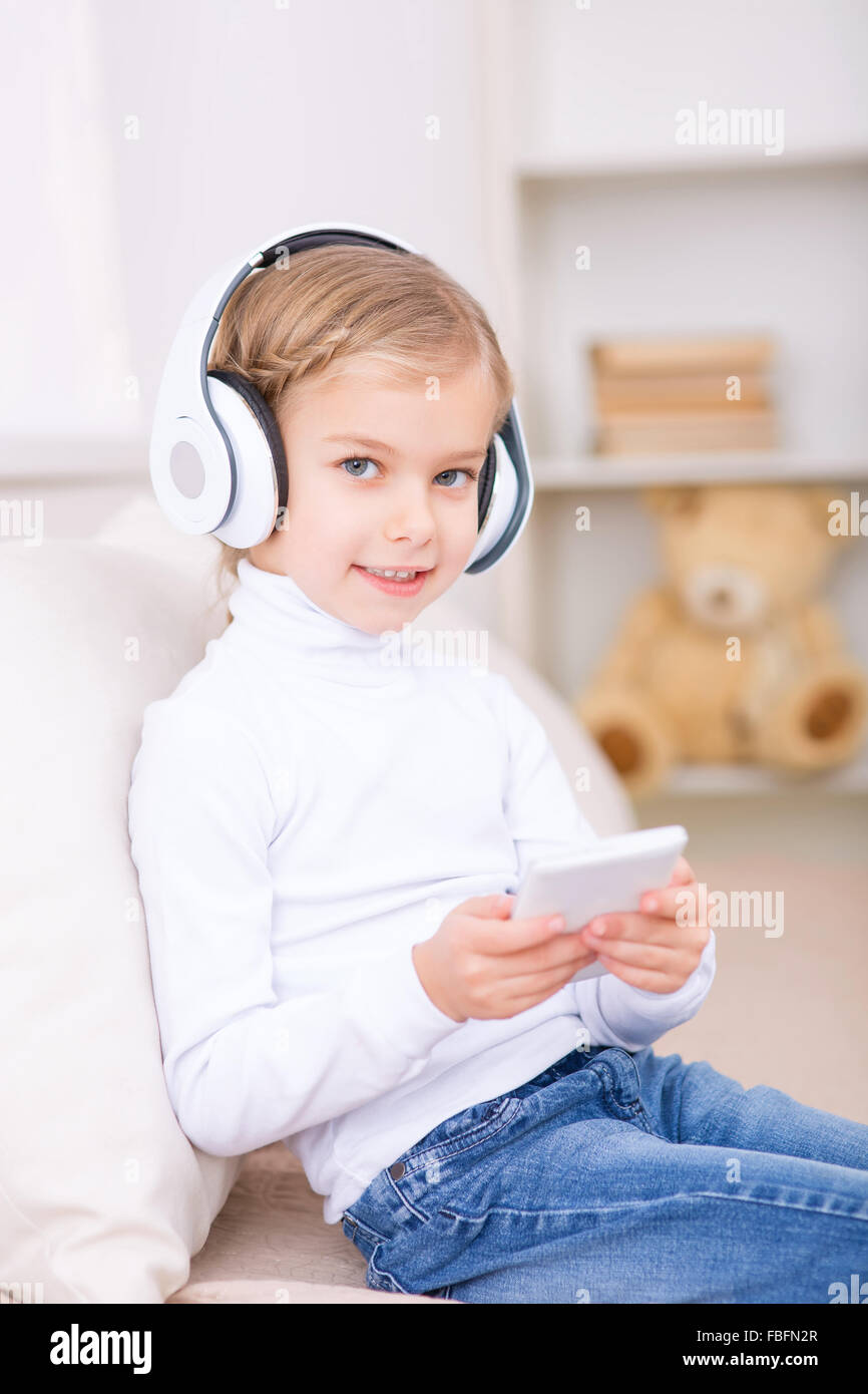Little girl in headphones is sitting on the sofa Stock Photo - Alamy