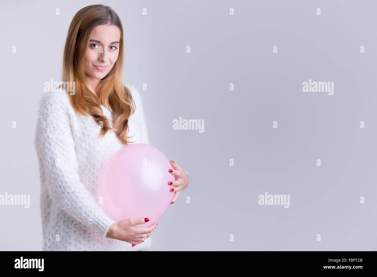 Woman holding a pink balloon to her belly. Concept of pregnancy. Stock Photo