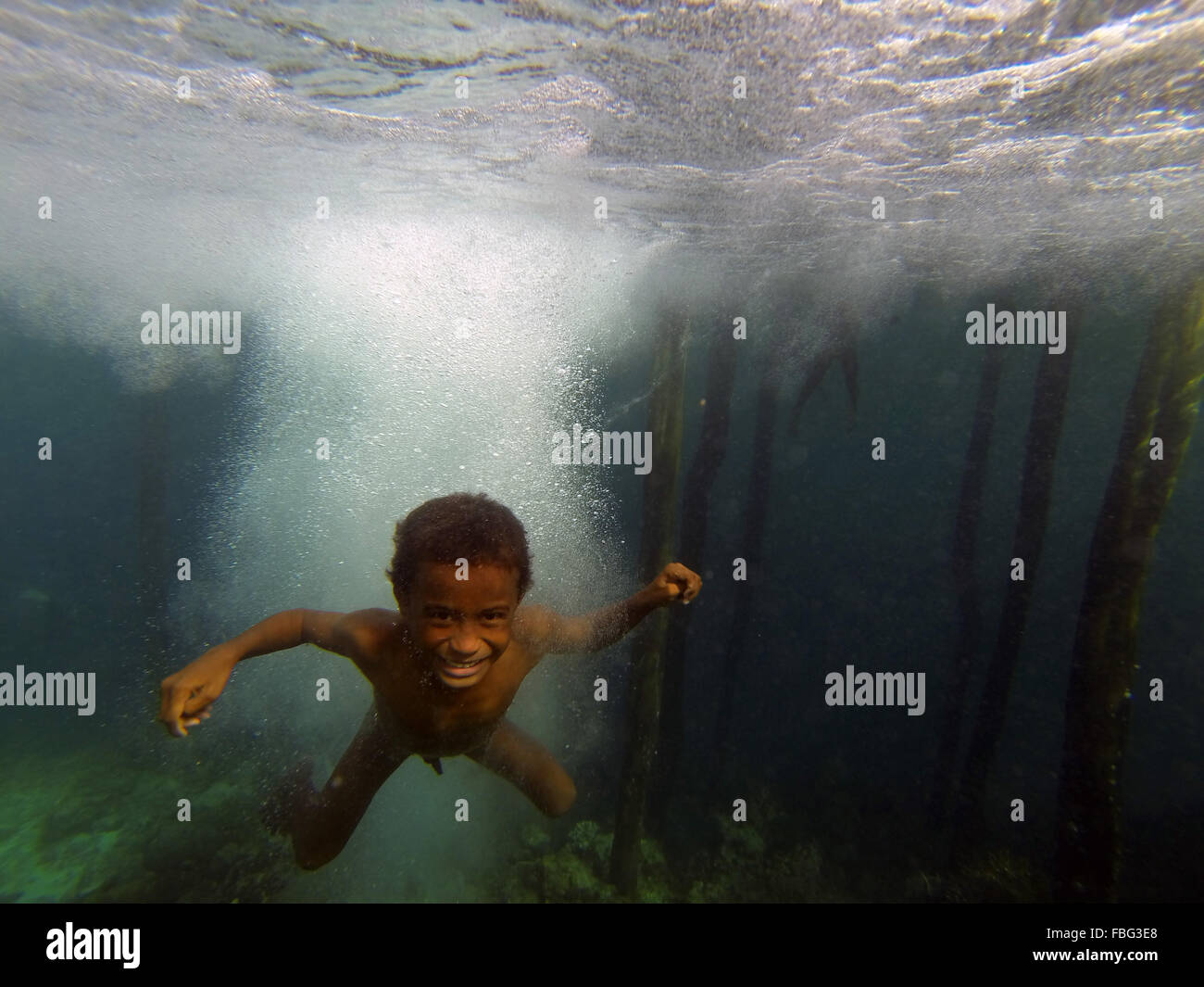Boy underwater after jumping off jetty, Gam Island, Raja Ampat, West