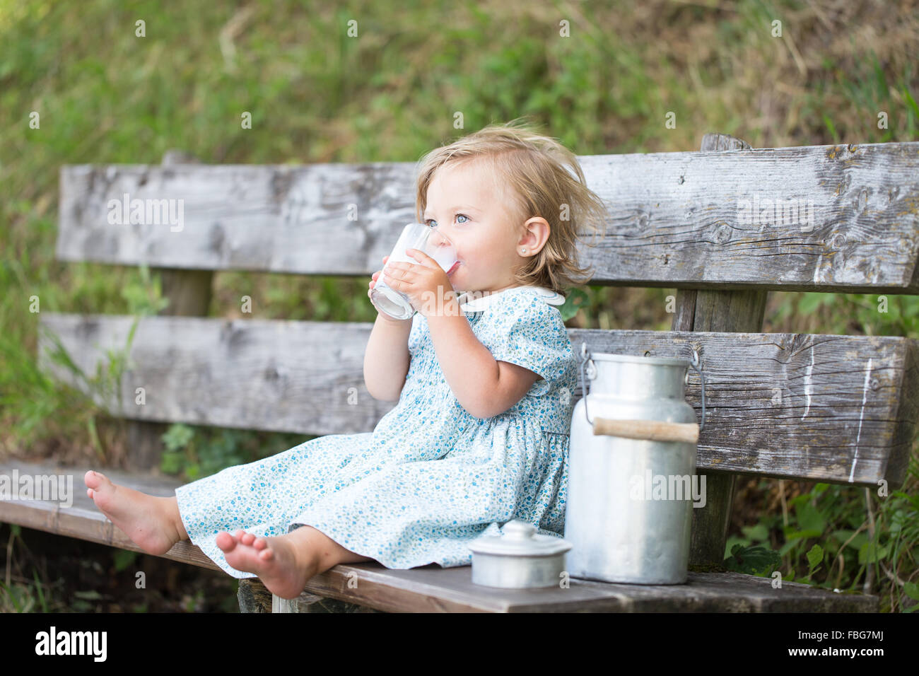 Girl drinking milk on a bench at an Alpine hut, Germany Stock Photo