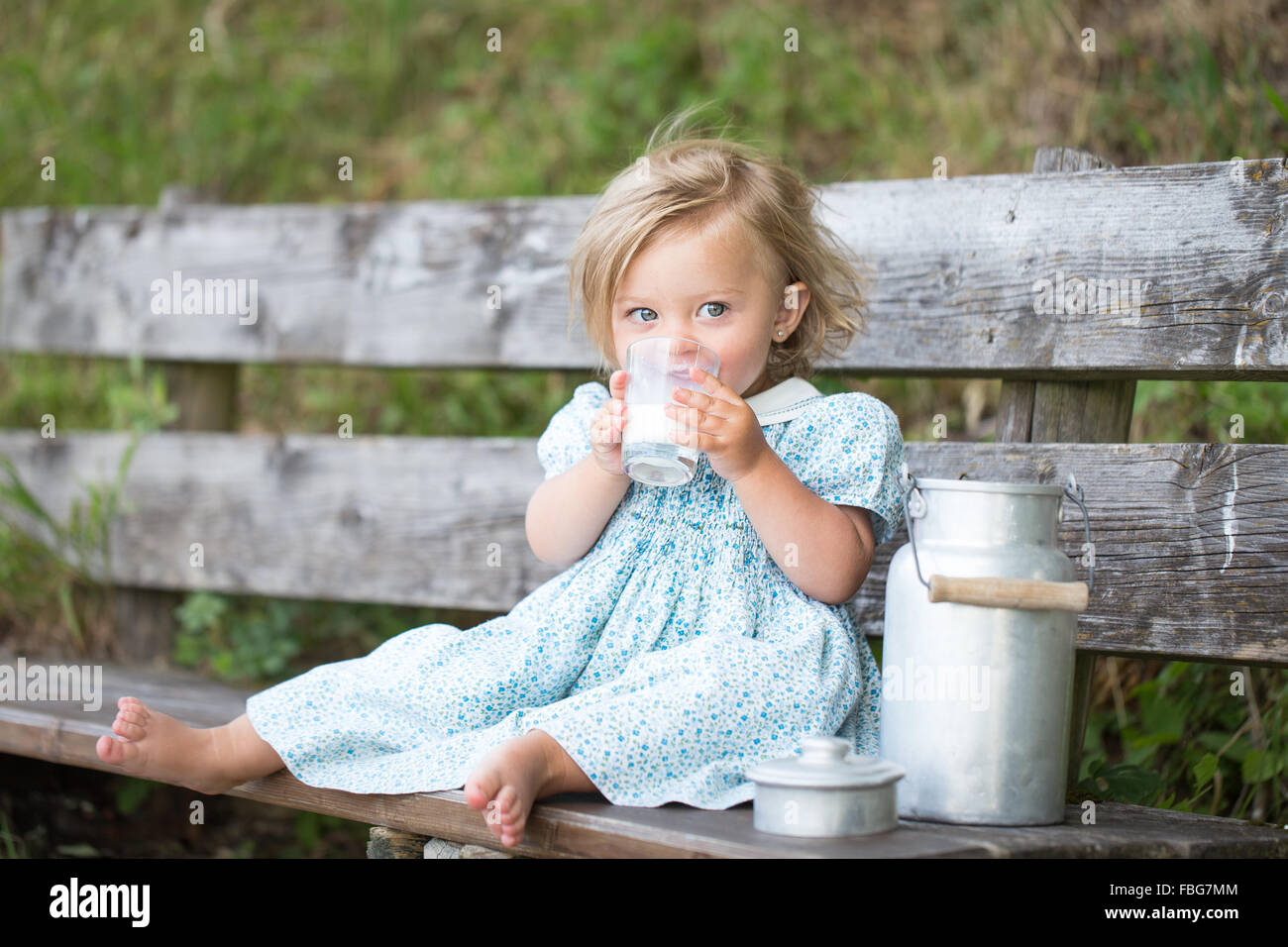 Girl drinking milk on a bench at an Alpine hut, Germany Stock Photo