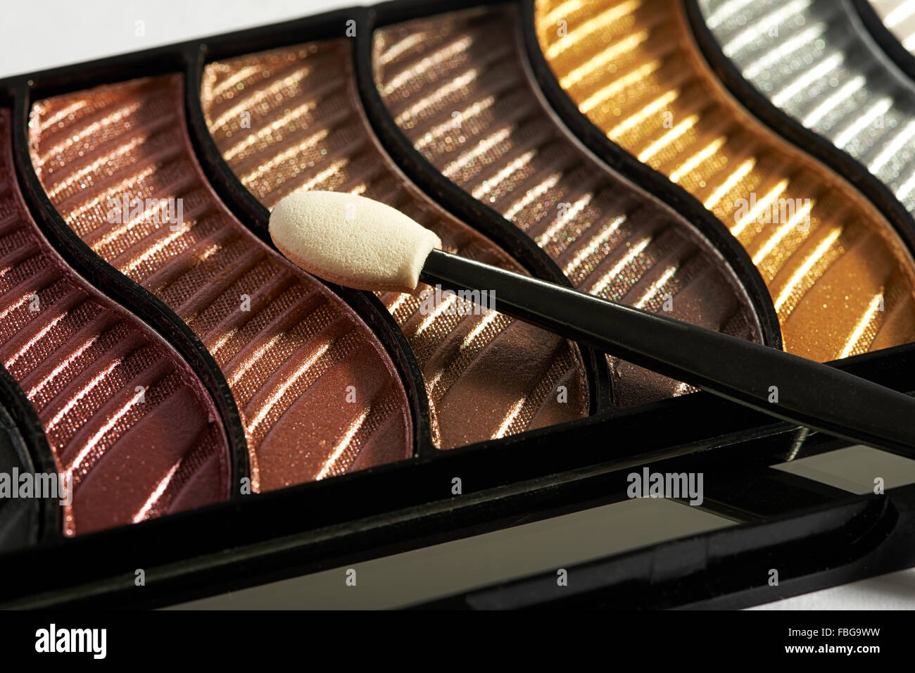 Close up view of compact makeup case with applicator on top of various eye shadow colors Stock Photo