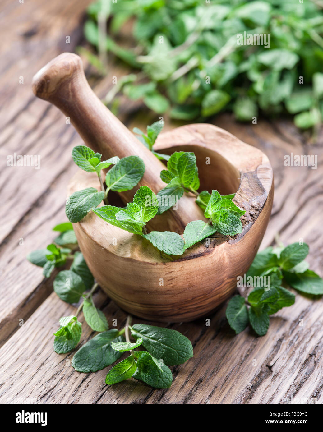 Fresh mint, wooden mortar and pestle on the old table. Stock Photo