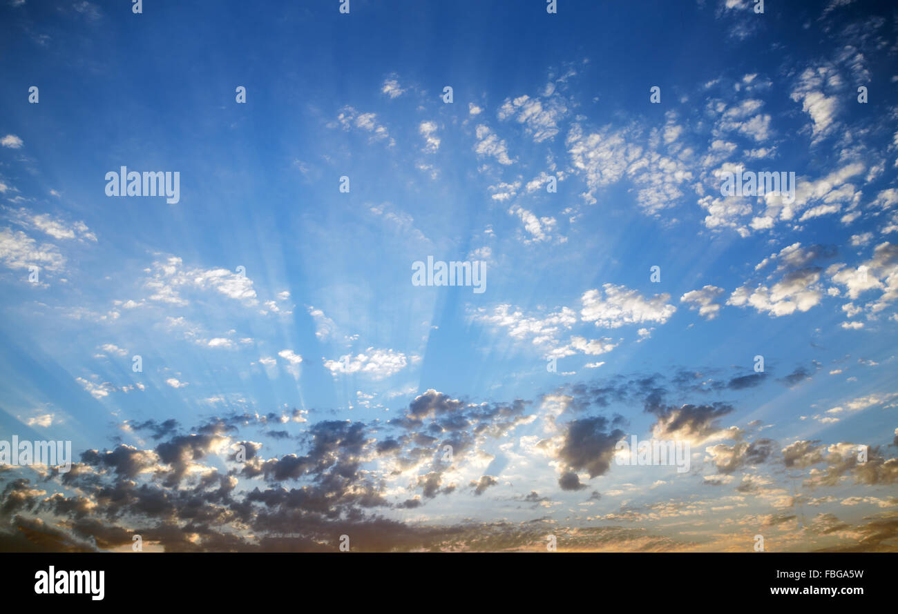 The rays of setting sun in the cloudy sky. Nature background. Stock Photo