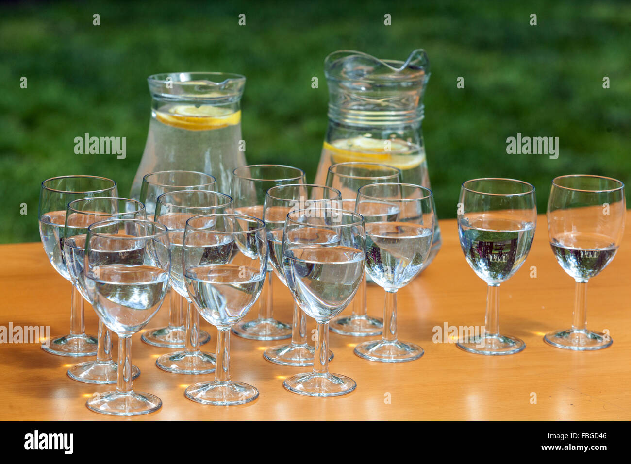 The two carafes of fresh lemon-flavored water and glasses on a table in the garden Stock Photo