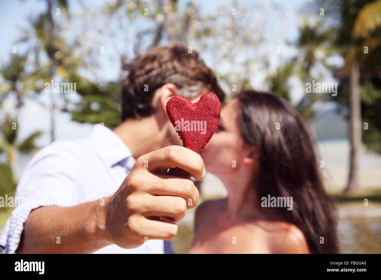 Happy couple kissing behind a red heart Stock Photo - Alamy