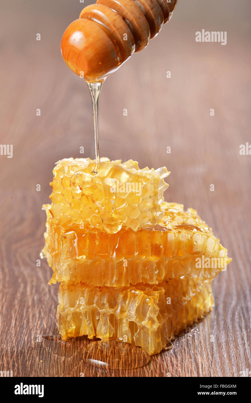Honey dripping on honeycombs on wooden background Stock Photo