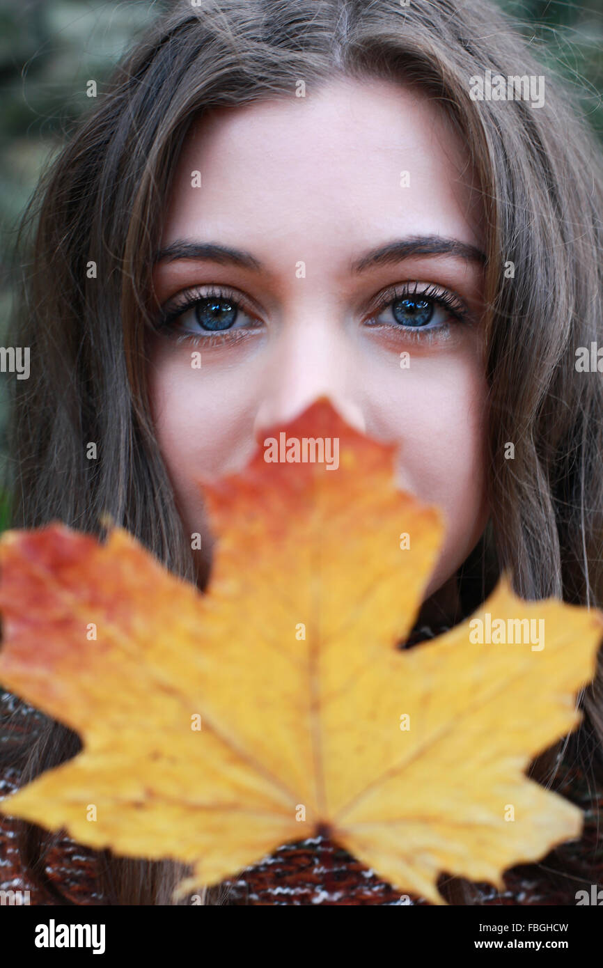 Portrait of a teenage girl holding a golden leaf to her face Stock ...