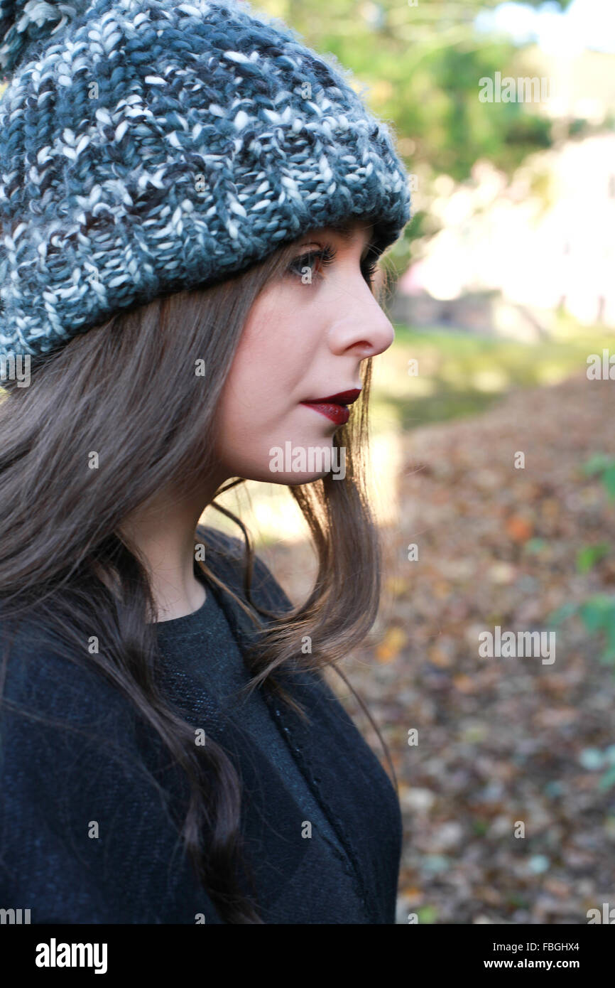 Profile a beautiful teenage girl wearing a pom pom hat at park Stock Photo - Alamy