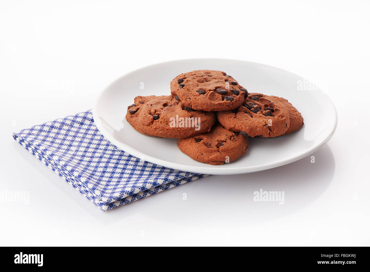 Pile of homemade chocolate chip cookies on white ceramic plate on blue napkin, isolated on white background Stock Photo