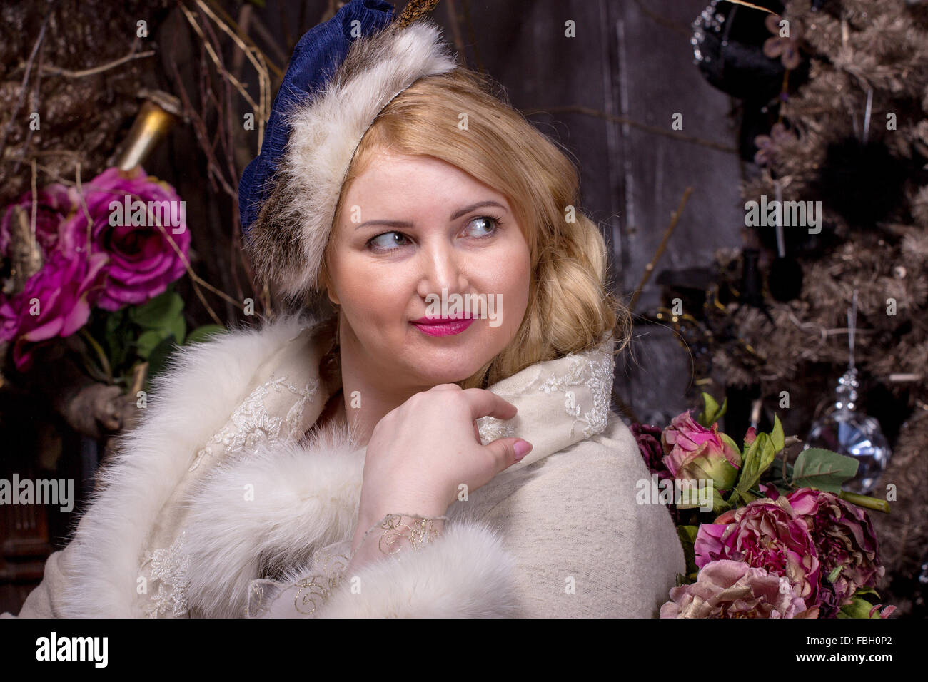 Pretty Plus size woman in coat with fur trim on dark flower background Stock Photo