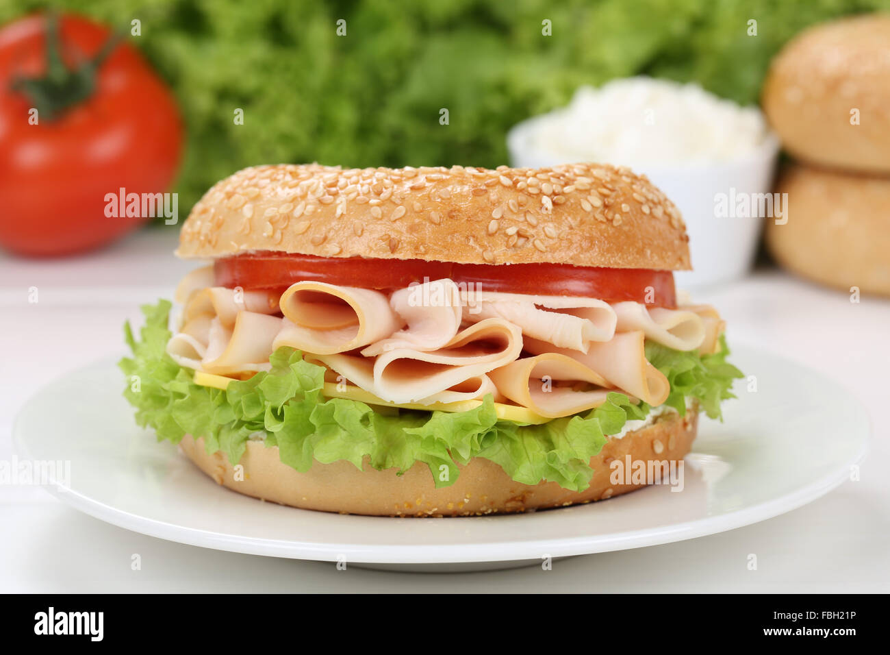 Bagel for breakfast with ham, cream cheese, tomatoes and lettuce Stock