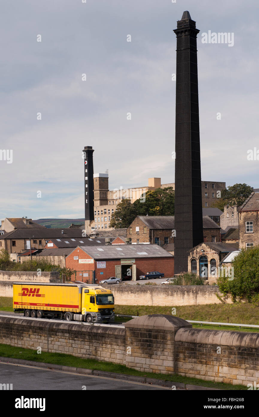 View across lorry on A650 Bingley Relief Road towards historic, tall black chimneys of 2 Victorian mills - one is the Damart  mill. England, GB, UK. Stock Photo