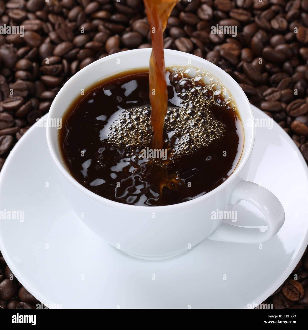 Hot fresh coffee drink pouring in cup with beans Stock Photo