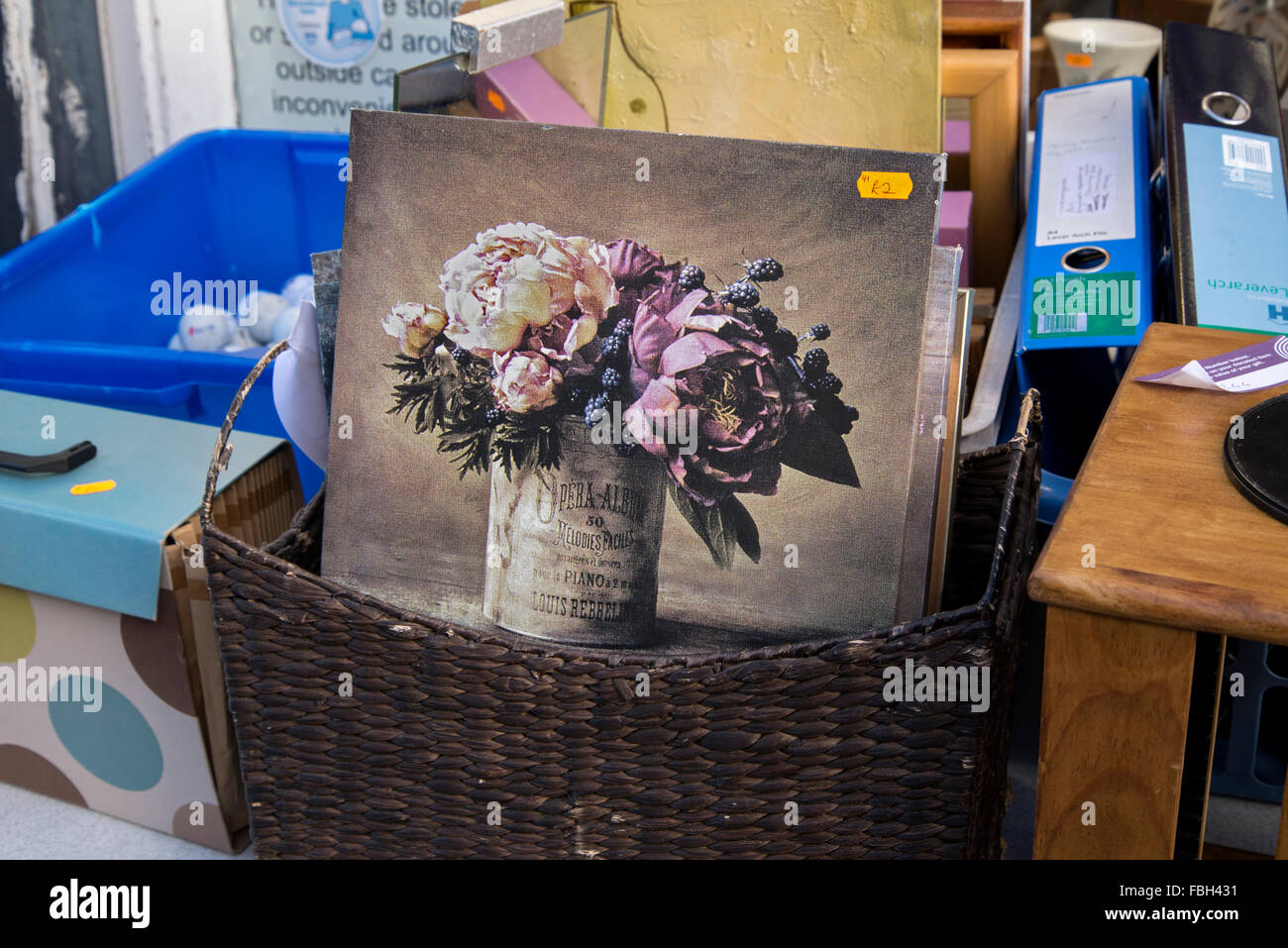 A basket containing a painting of a bunch of flowers outside a charity shop in Causewayside, Edinburgh, Scotland, UK. Stock Photo