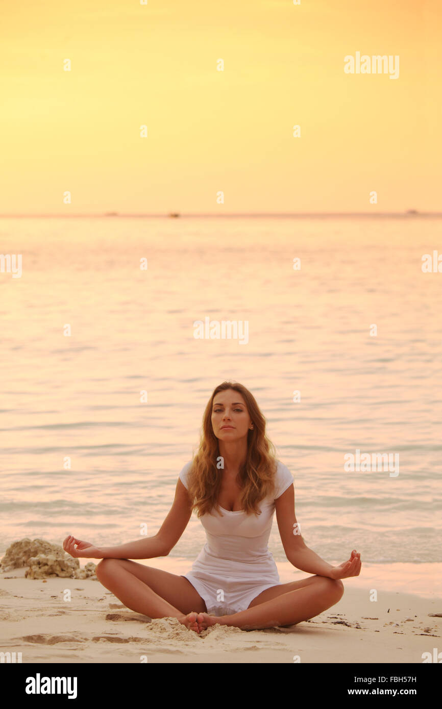Woman in lotus yoga pose at sunset on the beach Stock Photo - Alamy