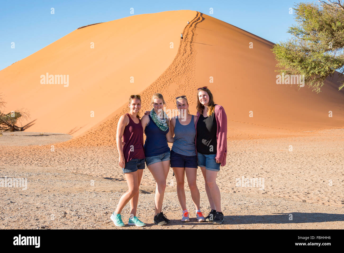 Young women by sand dune, Sossusvlei, Namib Desert, Namib-Naukluft Park, Hardap Region, Republic of Namibia Stock Photo