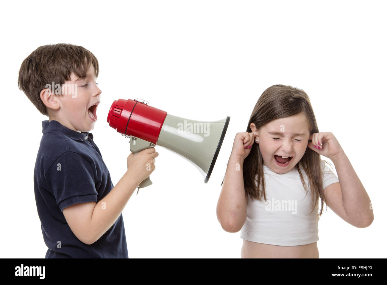 Young boy uses a bull horn to speak loudly into a girls ear Stock Photo