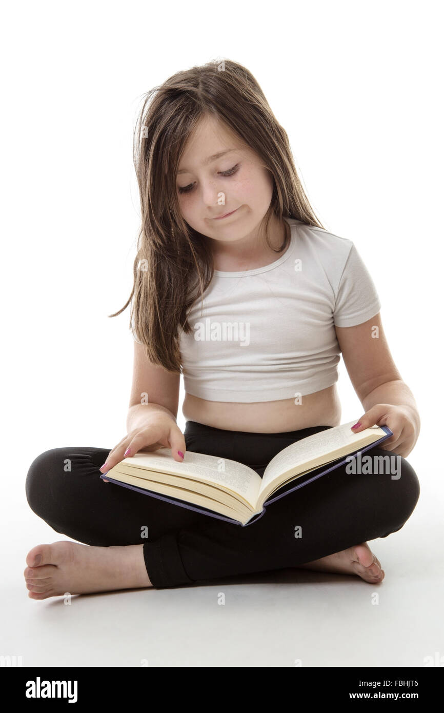 pretty young girl is sitting cross legged whilst reading her book