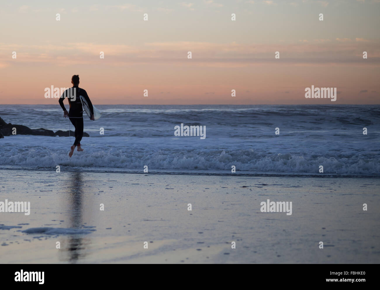 Surfer dashing out to the line up in an early morning surf session at Rockaway Beach, Queens, New York. Photographed on October Stock Photo