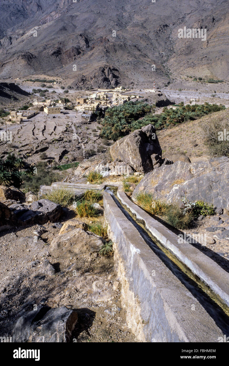 Wadi Bani Kharus, Oman.  Irrigation Canal (Falaj) Carries water down Mountainside to Village and date Palms below. Stock Photo