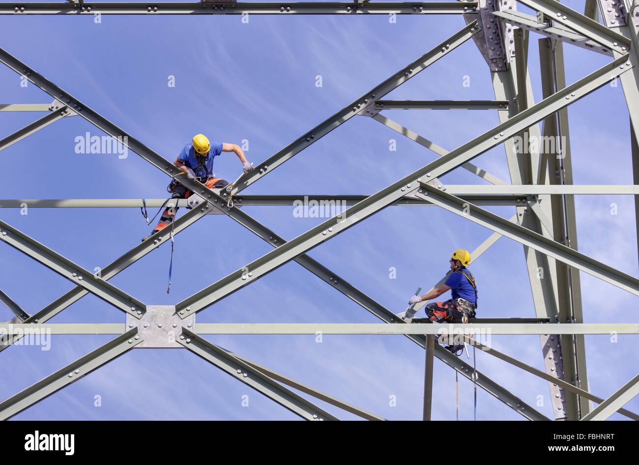 Two men screwing steel braces at a high-voltage power pylon, Thuringian Forest Stock Photo