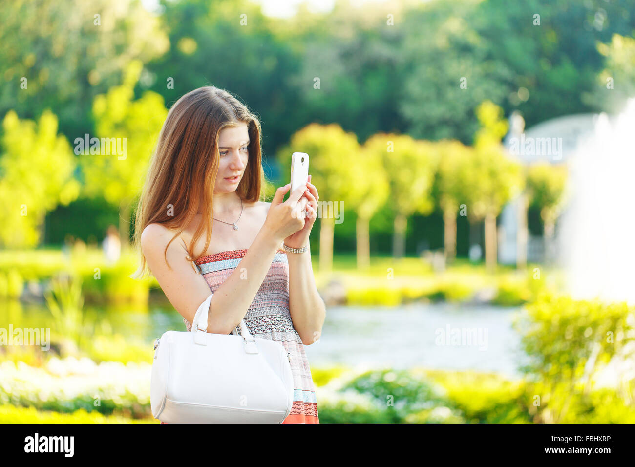 Beautiful young woman photographed on a mobile phone in the park Stock ...