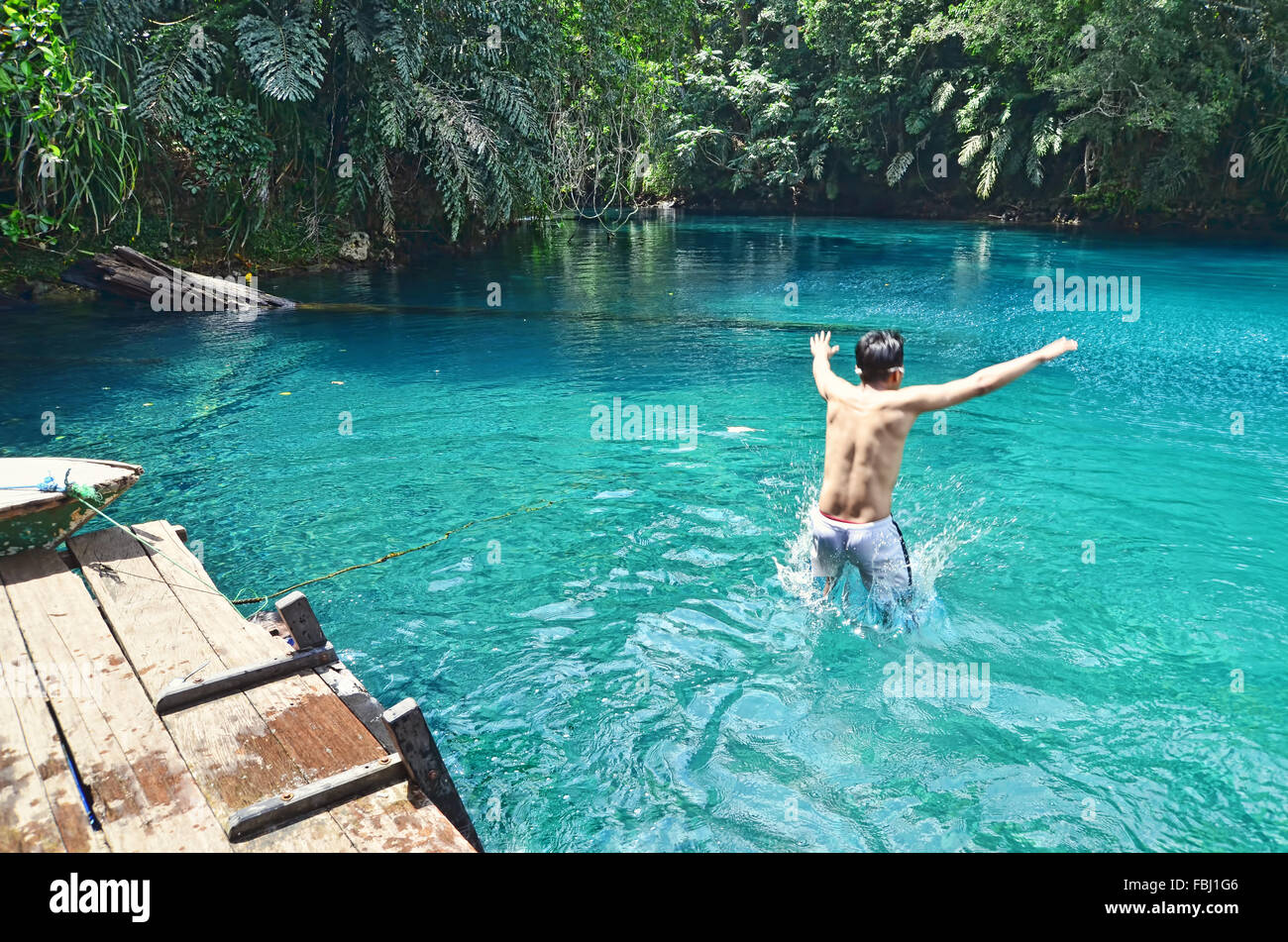 A boy jumping into Labuan Cermin Lake Stock Photo