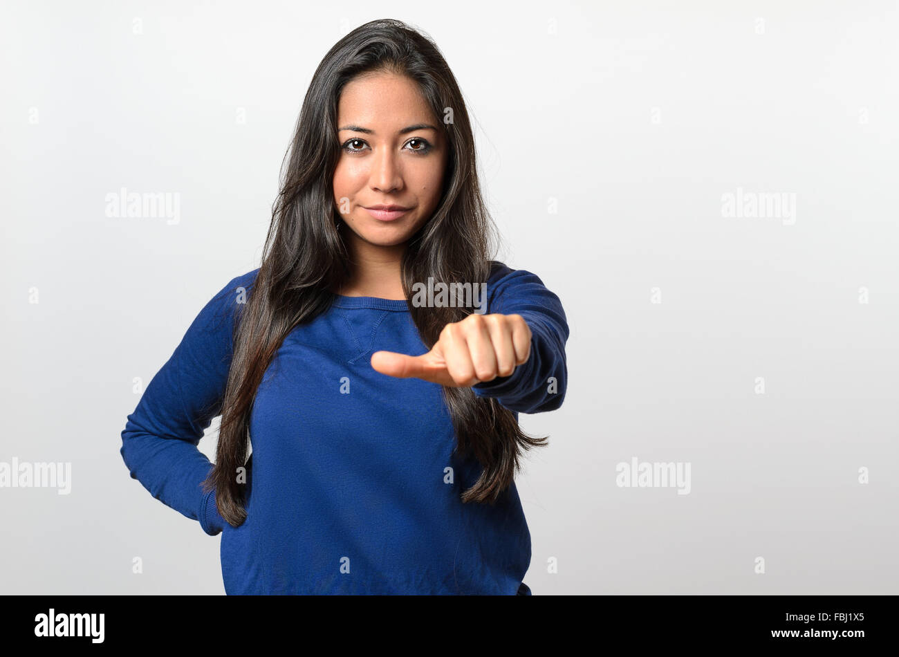 Woman giving an equal thumb gesture with a grimace showing that she is undecided, abstaining, impartial or indifferent in a vote Stock Photo