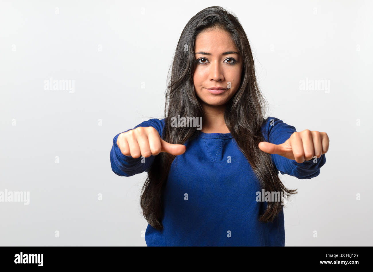 Woman giving an equal thumbs gesture with a grimace showing that she is undecided, abstaining, impartial or indifferent in a vot Stock Photo