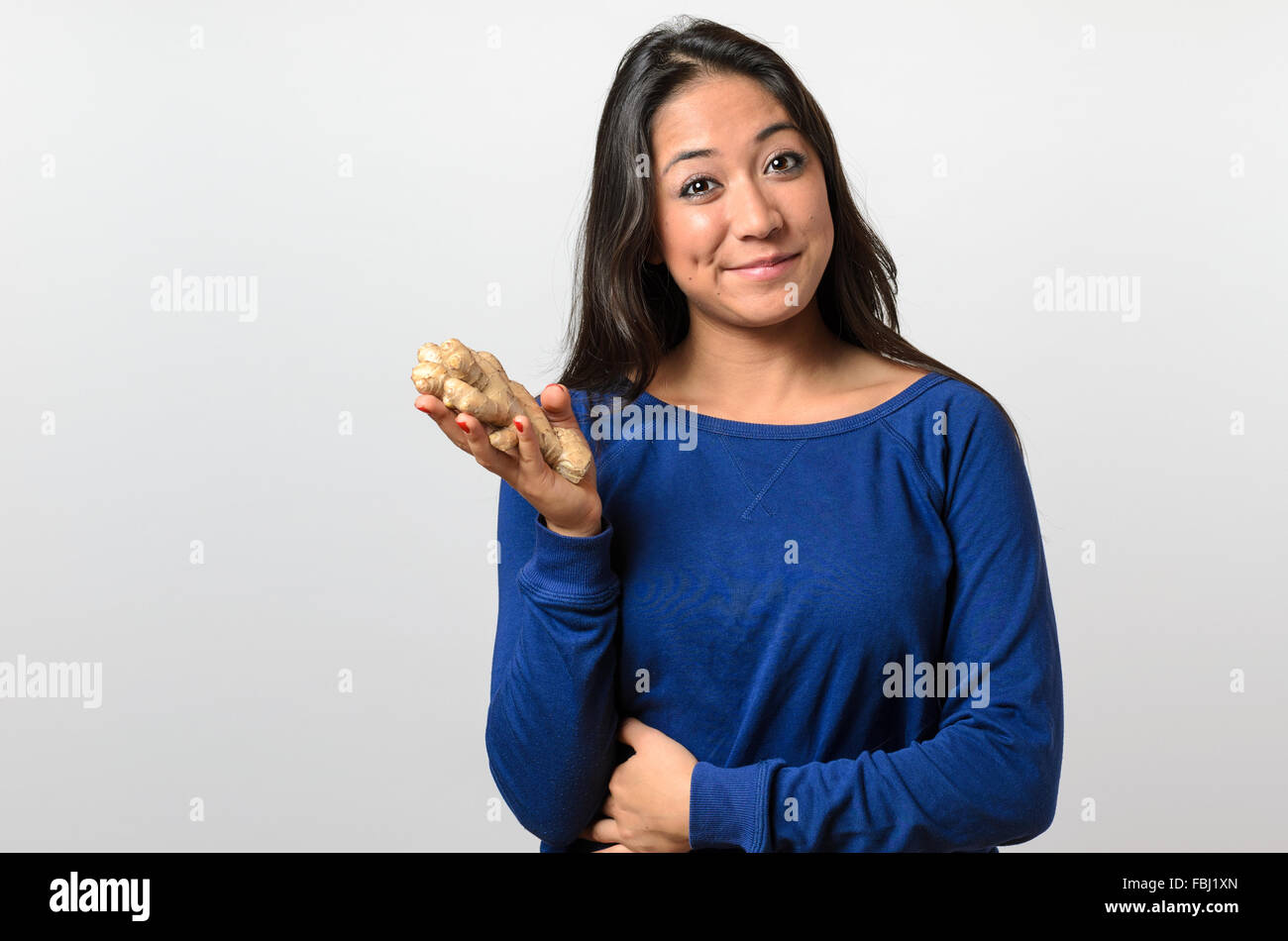 Healthy young woman holding a big ginger and smiling into the camera Stock Photo