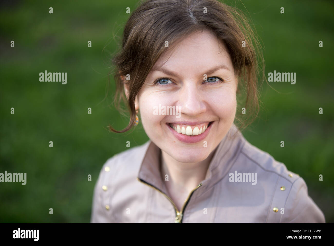 Headshot portrait of happy smiling woman in park Stock Photo