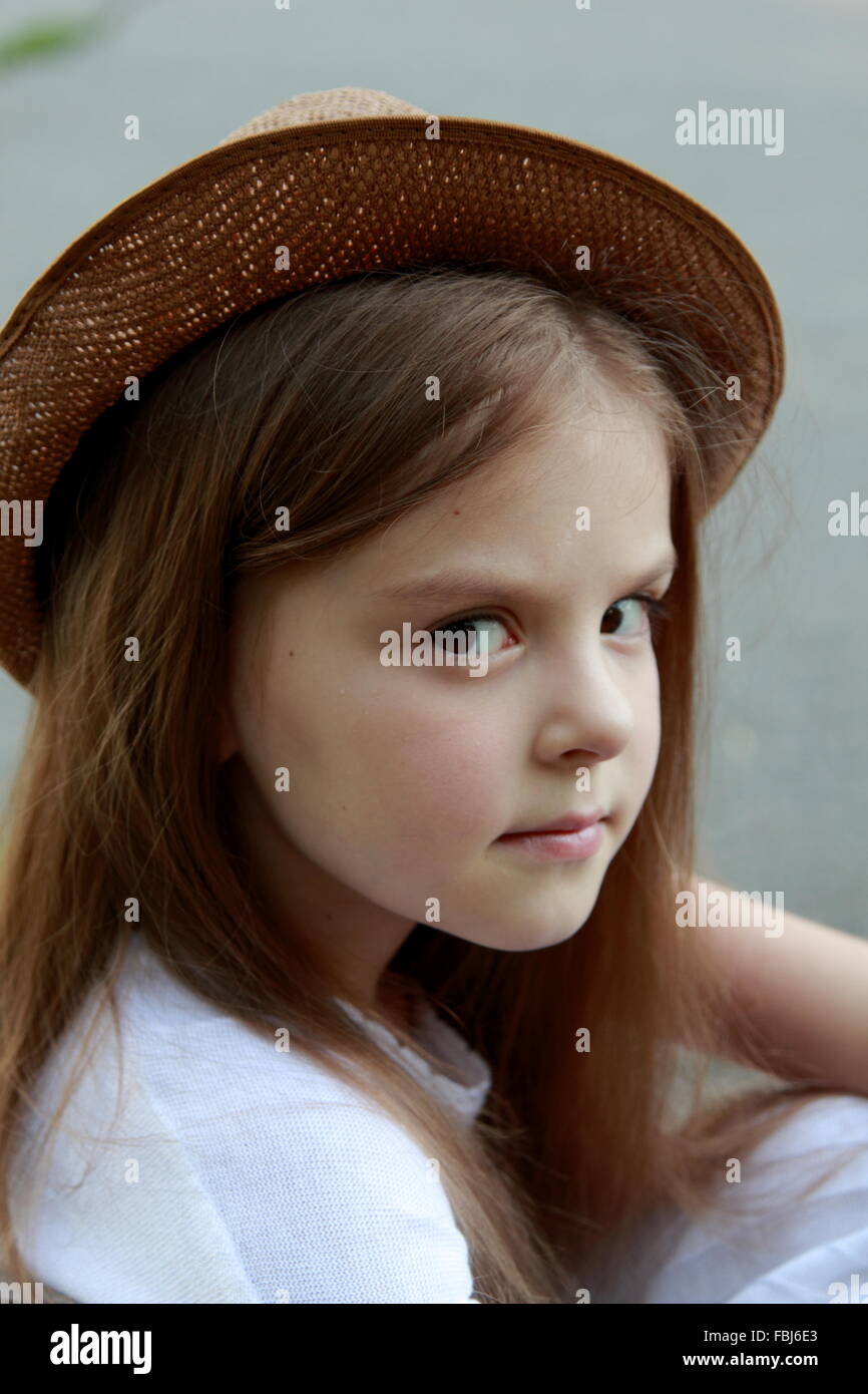 Portrait of a little girl in a white dress in a summer park sits on the ...
