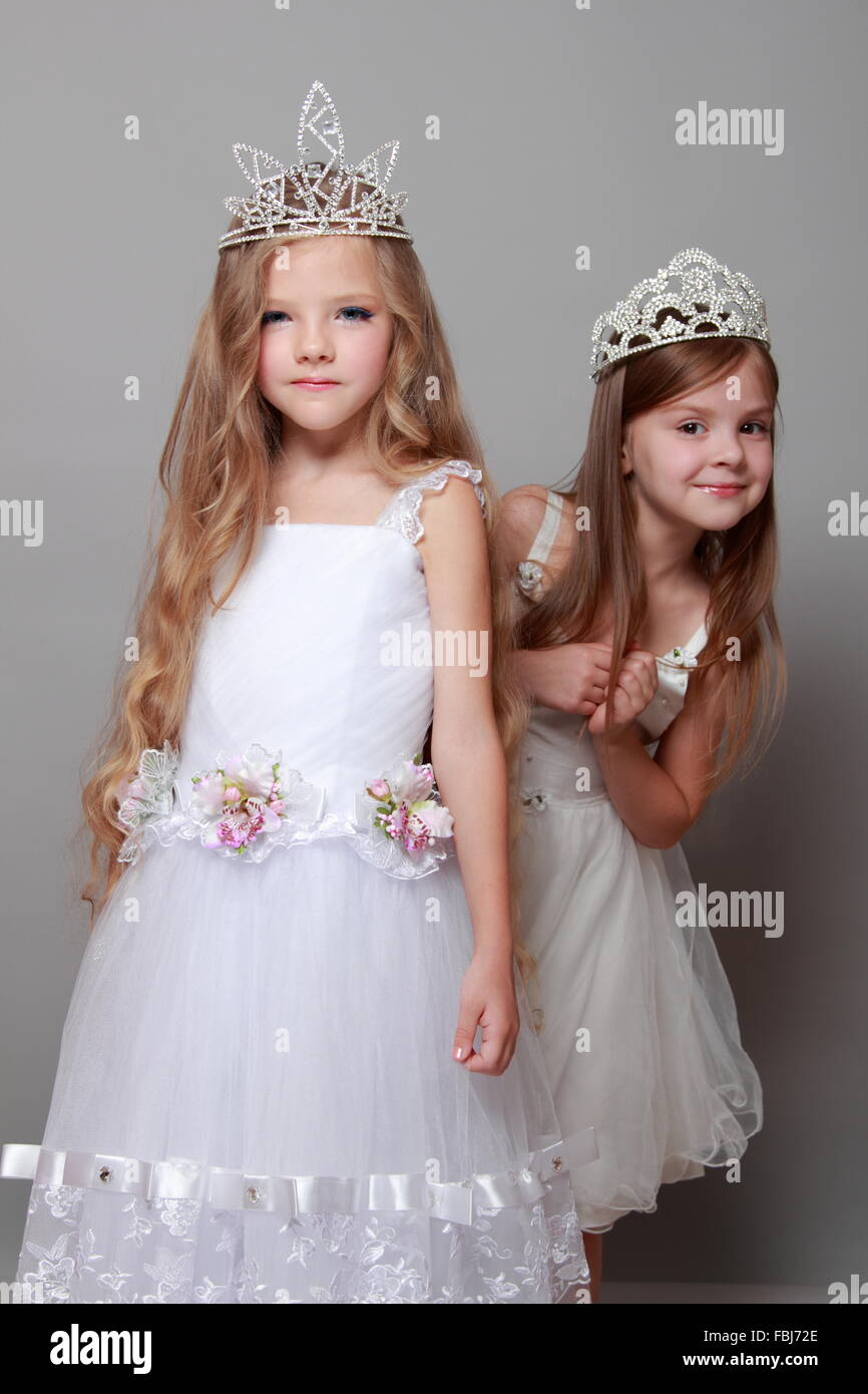 Charming and elegant little girls dressed in white and wearing a crown ...