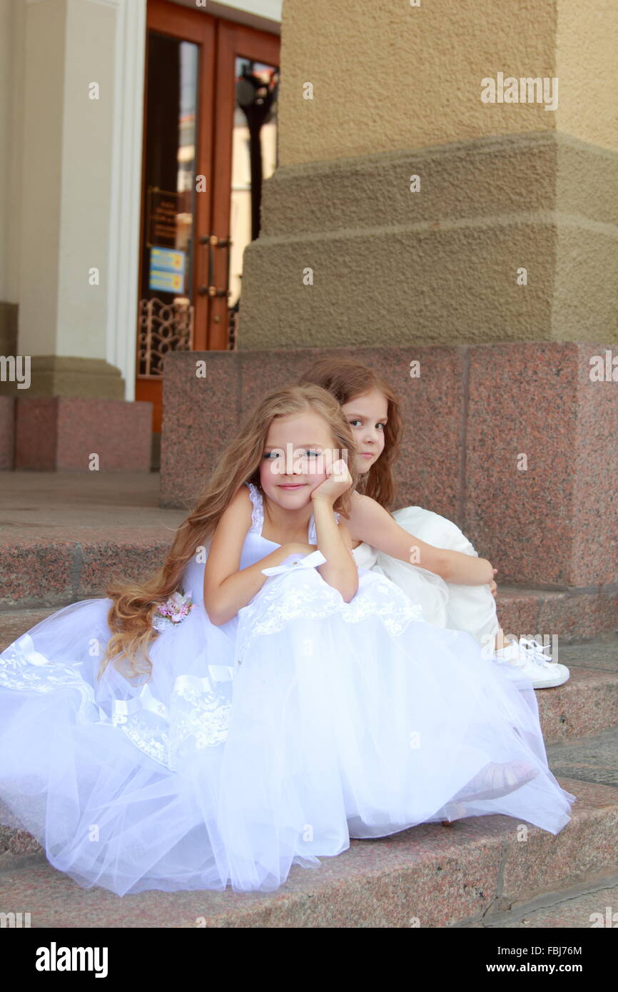 Charming young girl with long healthy hair in a beautiful white dress ...