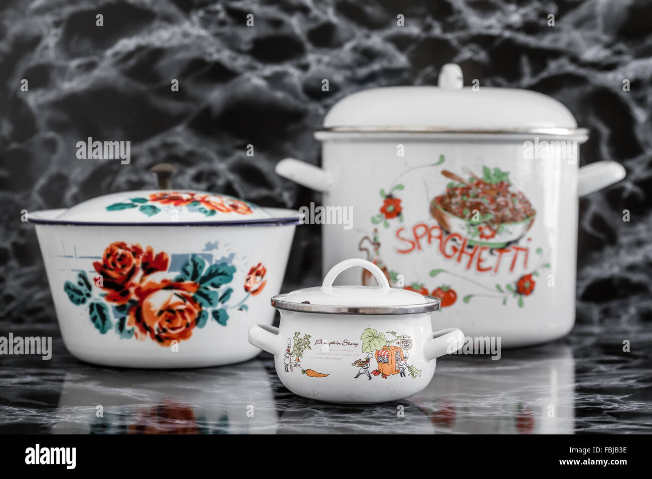 White vintage enamel saucepans with various designs on black marble background Stock Photo Alamy