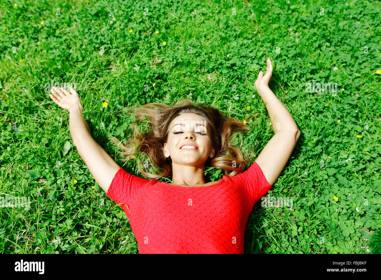 beautiful young woman in red dress lying on grass Stock Photo - Alamy