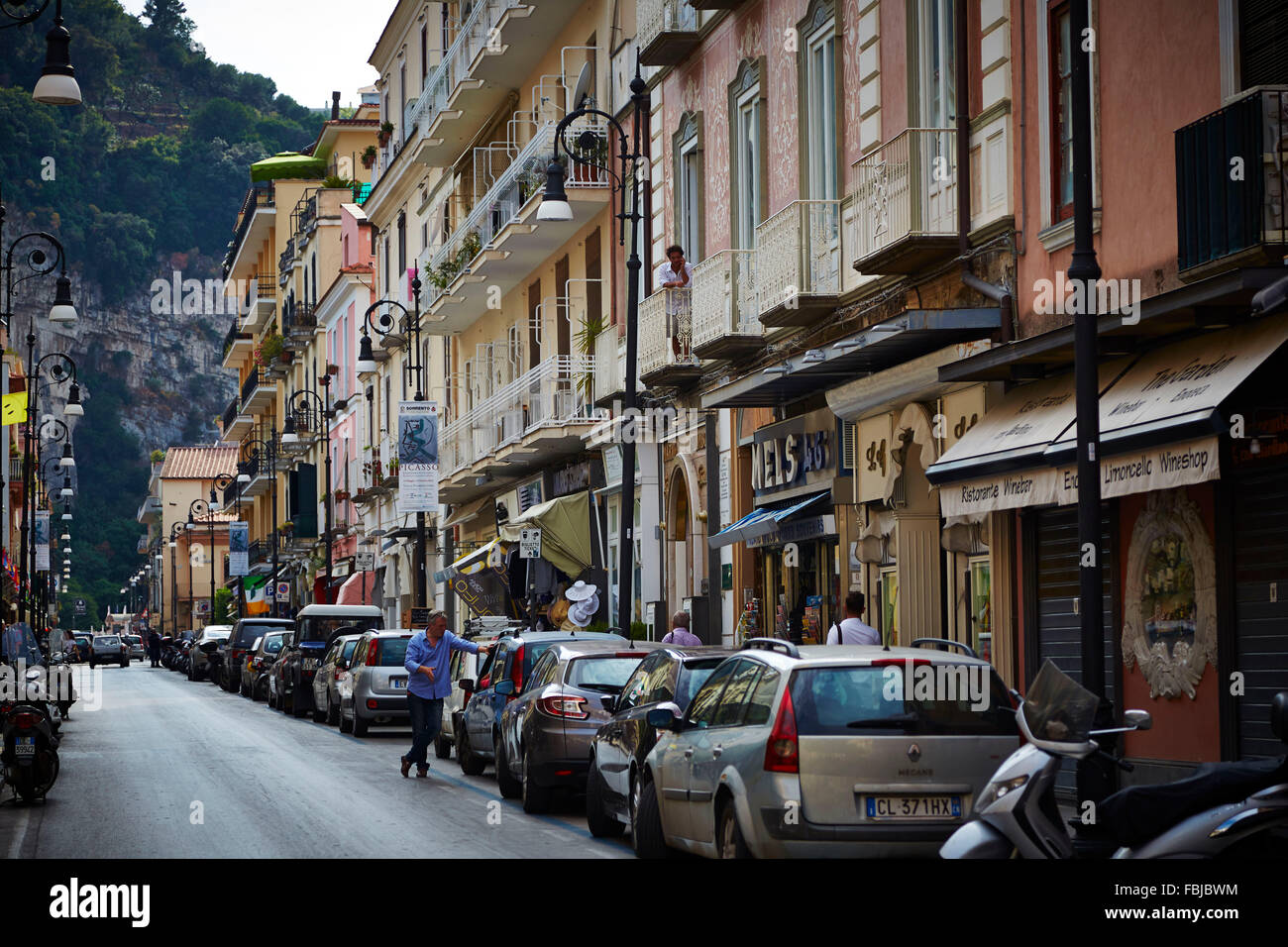 Street in Sorrento, row of houses, parking cars, man leaning against car, Amalfi Coast, Italy Stock Photo