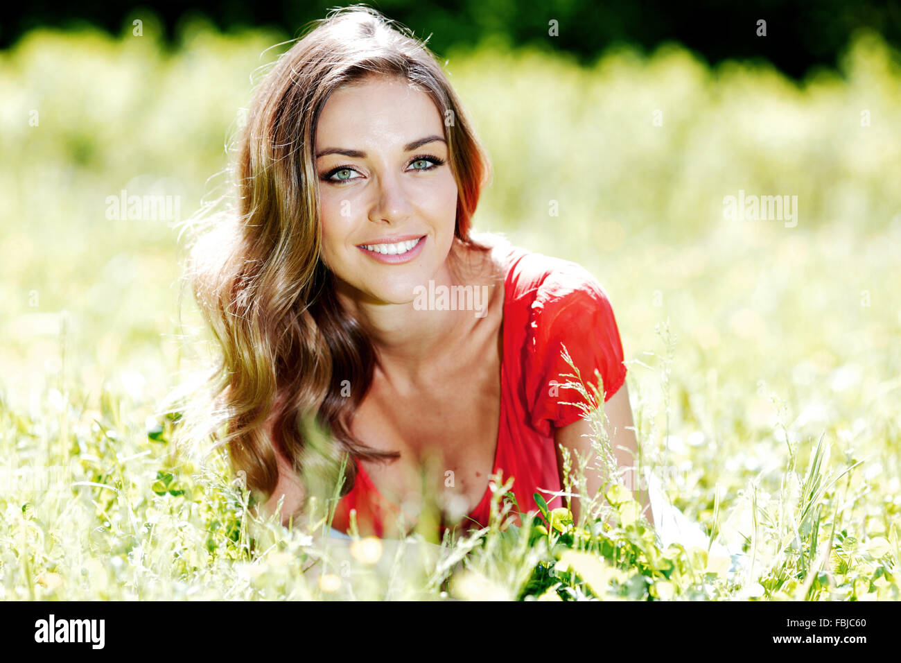 beautiful young woman in red dress lying on grass Stock Photo - Alamy