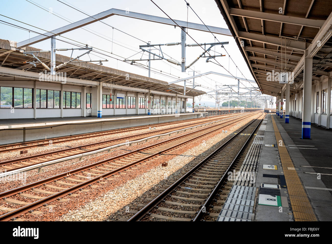 Train station loading platfowm with tracks Stock Photo