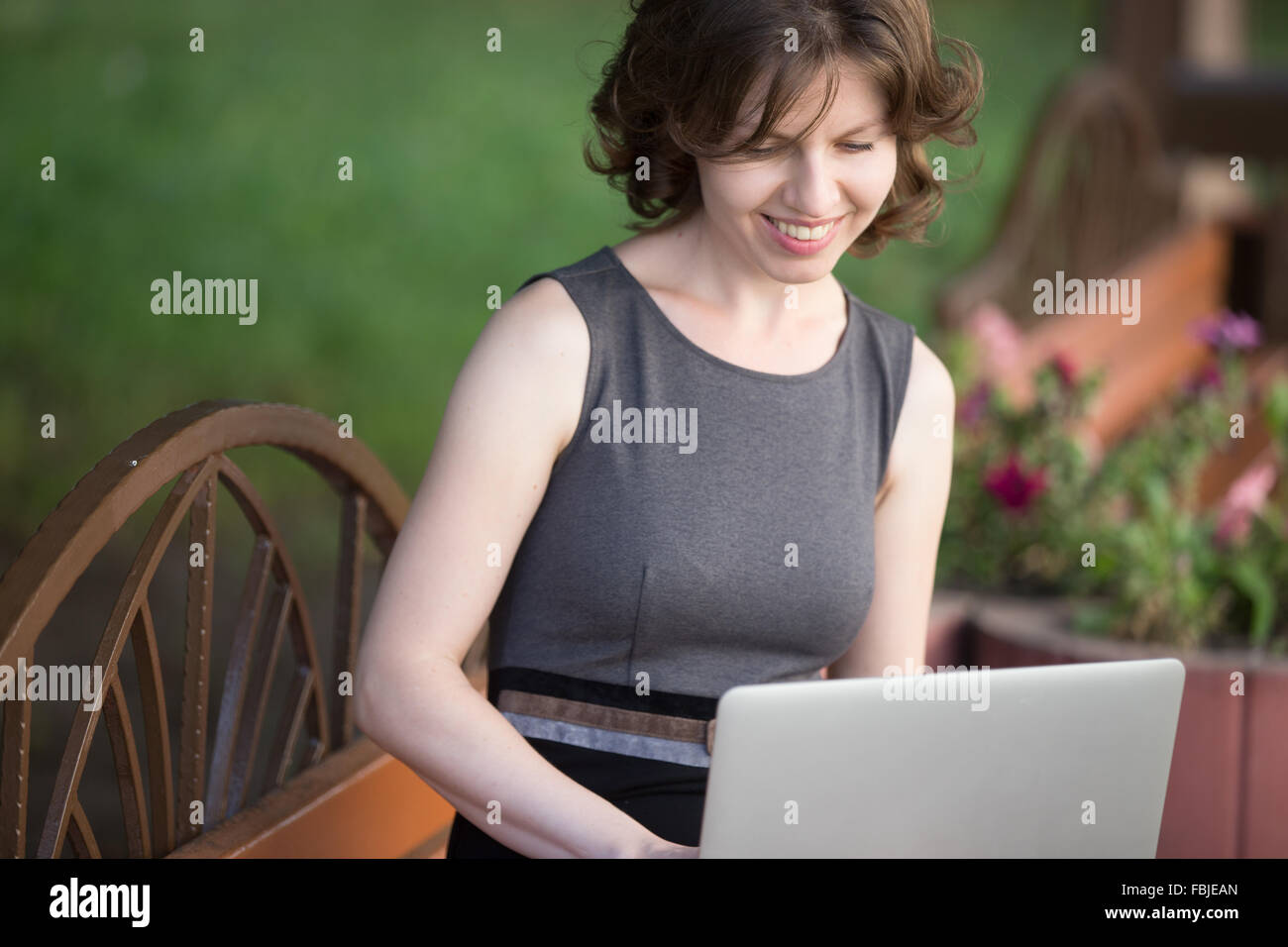 Portrait of happy smiling beautiful young woman sitting on bench on the ...