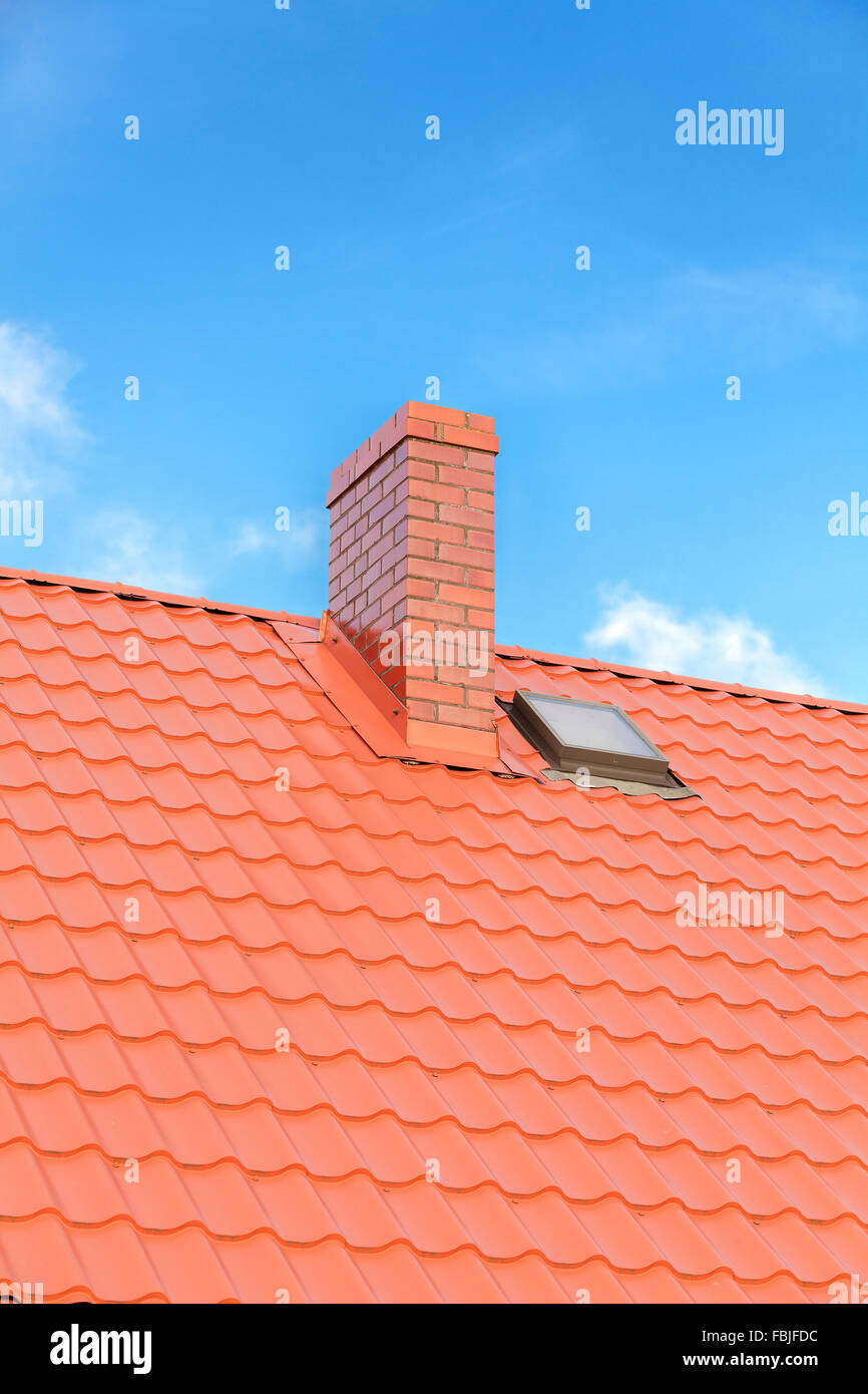 Roof with ceramic tile chimney against blue sky, space for text. Stock Photo