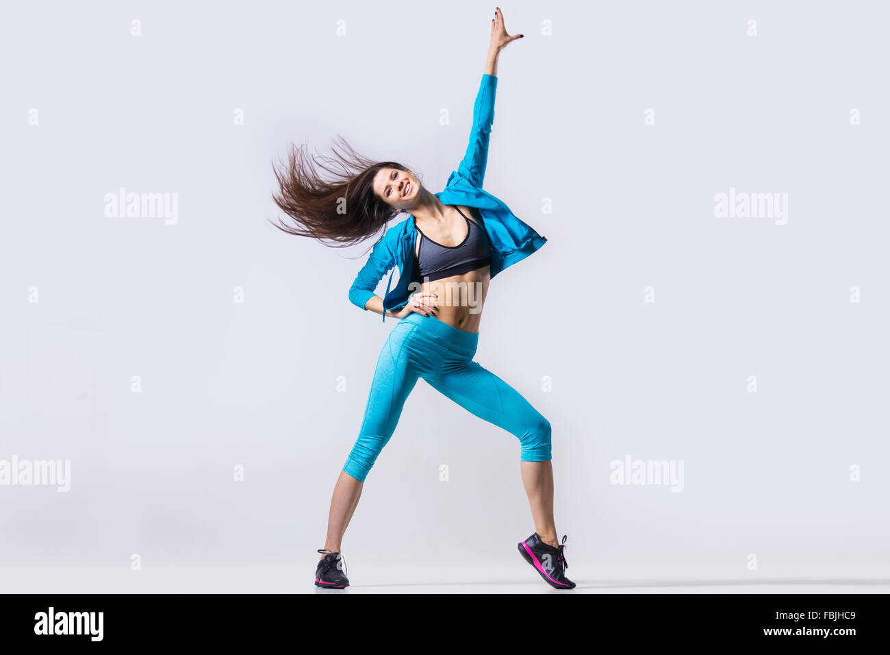 One happy smiling attractive gorgeous young fit modern woman in blue sportswear warming up, working out, dancing Stock Photo