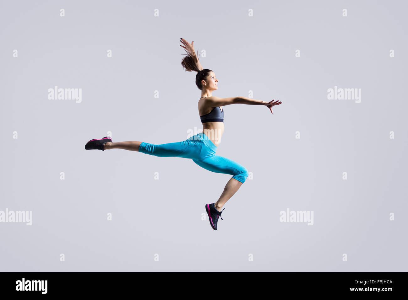 One attractive gorgeous young fit modern woman in blue sportswear with ponytail warming up, working out, dancing, jumping Stock Photo