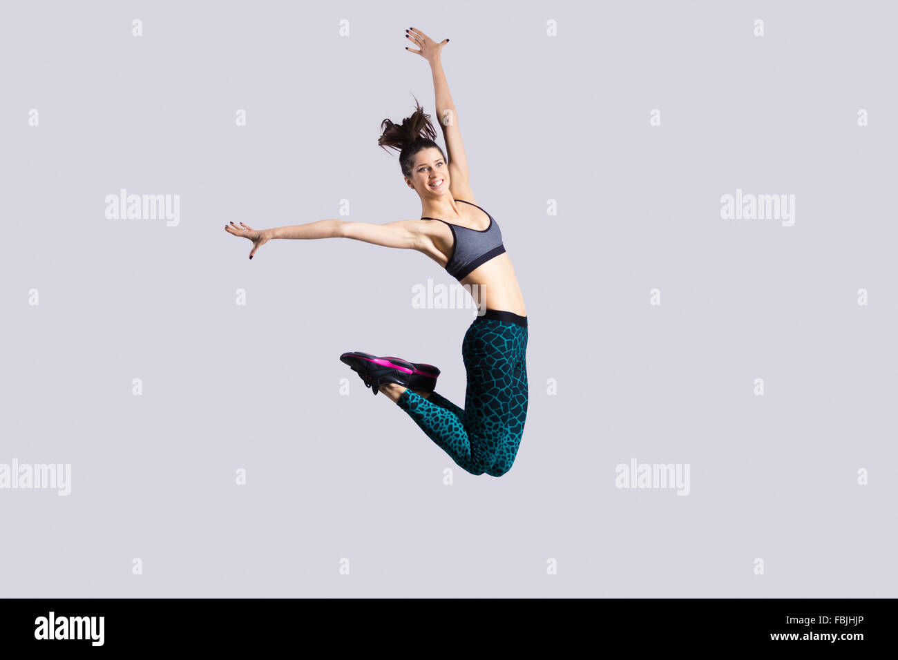 One happy attractive gorgeous young fit modern woman in aquamarine sportswear with ponytail working out, dancing, jumping Stock Photo