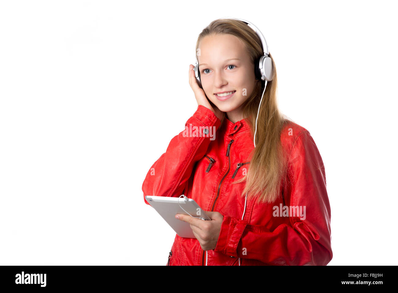 Portrait of happy beautiful casual teenage girl wearing red leather jacket and earphones using modern tablet, friendly smiling Stock Photo